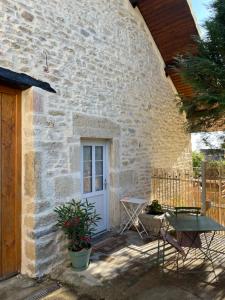 a stone house with a white door and a table at La Parenthèse, Les Gîtes de Montfaucon in Montfaucon