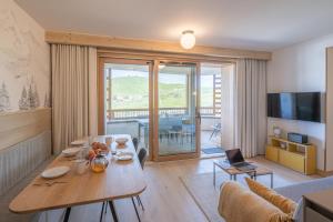 a living room with a wooden table and a living room with at Alpe d'Huez Houses - L'Emparis - PHOENIX3 - Pour 5 SKI IN SKI OUT Wellness et vue magnifique in L'Alpe-d'Huez