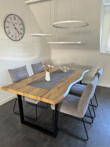 a dining room table with chairs and a clock on the wall at Ferienwohnung Maas in Ueß +1 photo