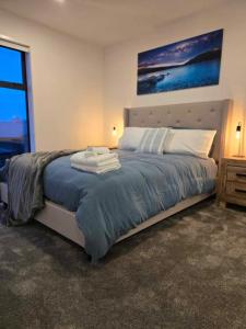 a bedroom with a large bed with a blue blanket at CBD Apartment 3 - 2 Bed 2 Bath in Christchurch