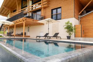 a swimming pool with two chairs and umbrellas next to a building at Schwarzwald Chalet Auwald in Freiamt