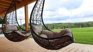 two hammocks hanging from a porch with a view of a field at Schwarzwald Chalet Auwald in Freiamt