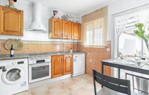 eine Küche mit Holzschränken, einer Waschmaschine und einem Trockner in der Unterkunft Nice Home In Chiclana De La Fronter in Chiclana de la Frontera