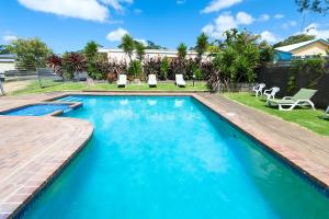 a swimming pool with a wooden deck and chairs in a yard at Motel Marengo in Apollo Bay
