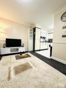 a living room with a flat screen tv and a table at Ibate Apartment, Basildon Essex in Nevendon