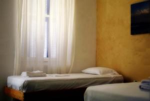 a bedroom with two beds and a window with white curtains at Thalassa4 in Andros