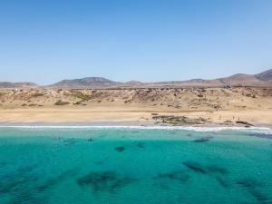 a body of water with a beach and mountains in the background at Casa Alicia - El Cotillo - 2 Camere, 2 Bagni in El Cotillo
