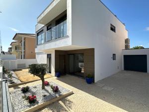 une maison blanche avec un arbre dans une cour dans l'établissement Maison bord mer près de le Lisbonne, à Charneca