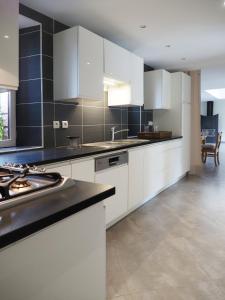 a kitchen with white cabinets and a black counter top at La Maison du Château de Sable in Porspoder