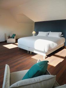 a bedroom with a large white bed and a couch at La Maison du Château de Sable in Porspoder