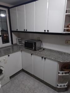 a kitchen with white cabinets and a microwave at Lage ,Costa da Morte, ruta dos faros, Galicia, playa in Laxe +1 photo