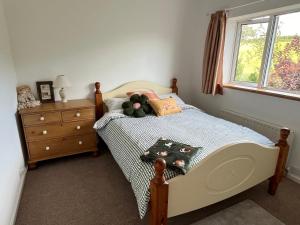 a bedroom with a bed and a dresser and a window at Beckbury Guesthouse in Beckbury