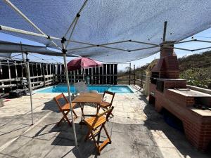 a patio with a table and chairs and an umbrella at Mística Suítes in São Thomé das Letras