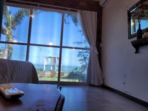 a living room with a large window with a view of the ocean at Villa Jardim Mar in Anchieta