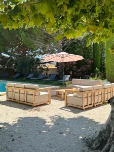 two couches and an umbrella next to a pool at Mas le petit Paradou in Paradou