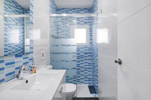 Un baño con inodoro blanco y azulejos azules. en Casa Orquidea, en El Palmar 18 fotos más