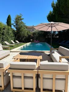a pool with a table and chairs and an umbrella at Mas le petit Paradou in Paradou