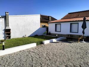 une maison avec une table et un banc dans une cour dans l'établissement Casa da Pitoquinha II, à Óbidos
