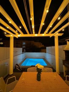 a swimming pool in a room with a table with flowers at Sand, Water & Sun House in Vila Nova De Cacela