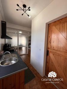 a bathroom with a sink and a wooden door at Casa de Campos AL in Angra do Heroísmo