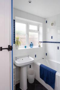 a white bathroom with a sink and a tub at Quaint 3 bed Cottage in central Dorking with parking in Dorking