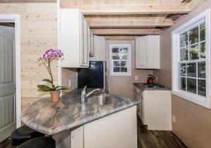 una cucina con mobili bianchi e un lavello di Bugsy's Mountain Retreat - Tiny House in the Trees a Lake Arrowhead