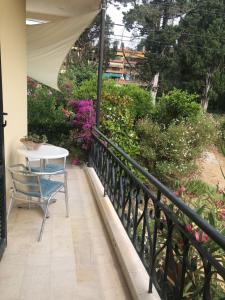 a table and chair on a balcony with flowers at MeadowView Spacious renovated ground floor studio in Análipsis