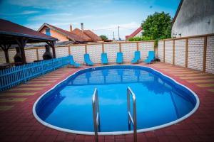 a swimming pool on a patio with blue chairs at Penzion SUNGARDEN-Veľký Meder in Veľký Meder