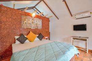 a bedroom with a bed and a brick wall at Golden Rice Resort & Cottages in Candolim