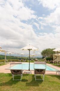 two chairs and an umbrella next to a swimming pool at Relais di campagna la polledrara in Paliano