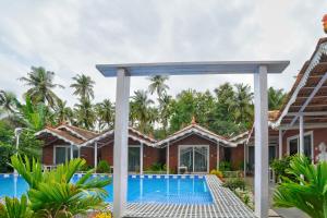 a villa with a swimming pool in front of a house at Golden Rice Resort & Cottages in Candolim