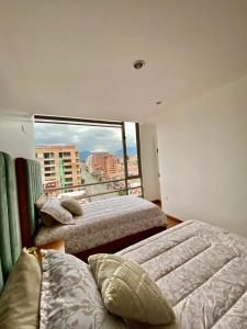 three beds in a room with a large window at Departamento de Lujo, Cuenca, Adrianashome in Cuenca