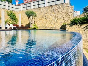 - une piscine en face d'un mur en pierre dans l'établissement GLICINIAS Cascais Villa, à Birre
