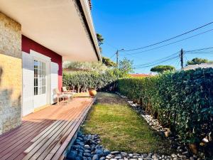 une maison avec une terrasse en bois à côté d'une haie dans l'établissement GLICINIAS Cascais Villa, à Birre