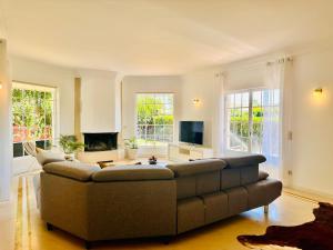 un salon avec un canapé et une télévision dans l'établissement GLICINIAS Cascais Villa, à Birre