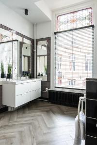 a bathroom with a sink and two windows at City Center Poppodium 013 Stadsvilla Tilburg in Tilburg