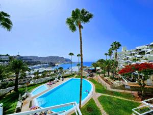 a view of a swimming pool with palm trees and the ocean at Wonderful Ocean View in Playa del Cura