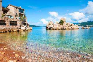 a beach with rocks in the water next to a building at Sunset Poolside Retreat BlueH in Budva