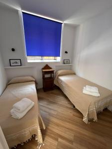 two beds in a room with a large window at Aires de la Bahia in San Fernando