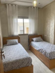 zwei Betten in einem Schlafzimmer mit Fenster in der Unterkunft Housse Fez City in Fès