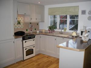uma cozinha com armários brancos e um forno com placa de fogão em The Homecoming Barn em Clogher