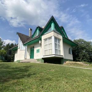 a green and white house on a grass field at Greenhouse Apartman in Zalakaros