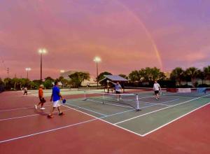 a group of people playing tennis on a tennis court with a rainbow at Sand Dollar Studio Pool Daily Rentals in Sarasota