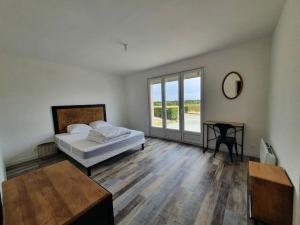 ein Schlafzimmer mit einem Bett und einem Tisch und einem Fenster in der Unterkunft Gîte de campagne 14 personnes in Bégrolles-en-Mauges + 20 Fotos