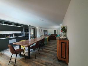 ein Esszimmer und eine Küche mit einem langen Tisch und Stühlen in der Unterkunft Gîte de campagne 14 personnes in Bégrolles-en-Mauges