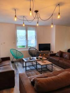 ein Wohnzimmer mit Sofa und Tisch in der Unterkunft Gîte de campagne 14 personnes in Bégrolles-en-Mauges