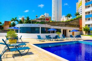 a pool with chairs and umbrellas next to a building at TerrazzoPontaNegraDJ in Natal