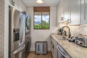 a kitchen with a stainless steel refrigerator and a window at Chic Condo— Renovated & Refurnished 2023 / 2024 in Wailuku