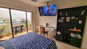 a bedroom with a bed and a desk and a tv at Habitación con Baño privado en Departamento Compartido in Lima