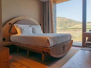 Un dormitorio con una cama grande con una ventana grande. en Barrilario Douro Wine Hotel e Spa - Quinta São Jose do Barrilario, en Armamar